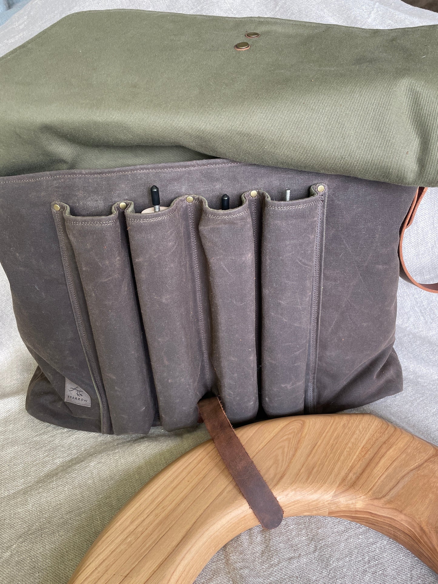 Attune crossbody bag in chocolate waxed canvas and olive green denim lining, for birthing stool. Leather strap, 4 leg pockets.