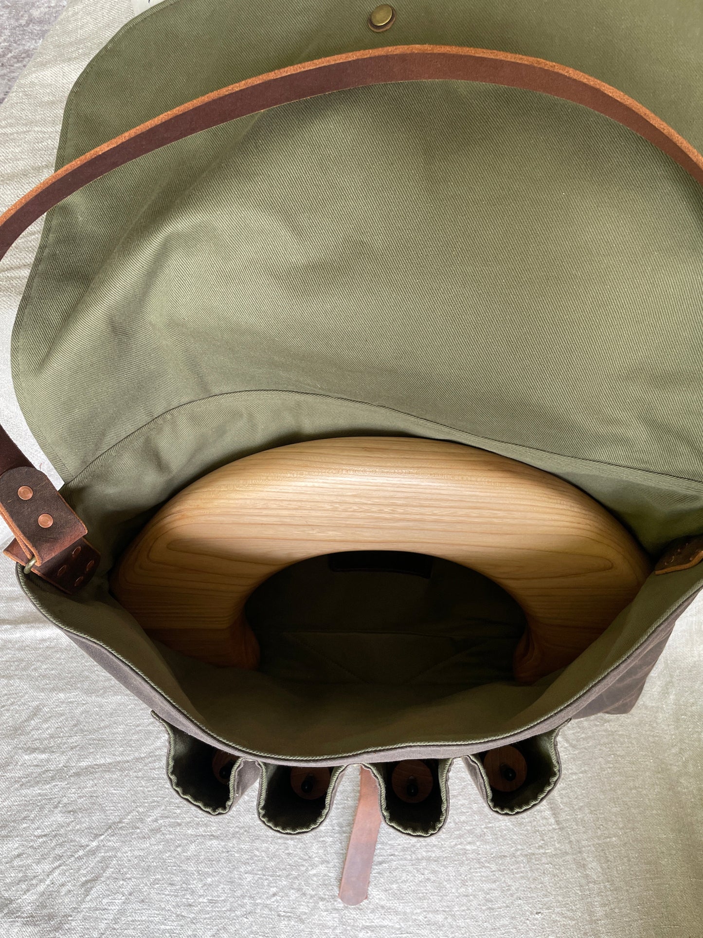 Top view of Attune crossbody bag in chocolate waxed canvas and olive green denim lining, for birthing stool. Shows the birthing stool seat and 4 legs in place.