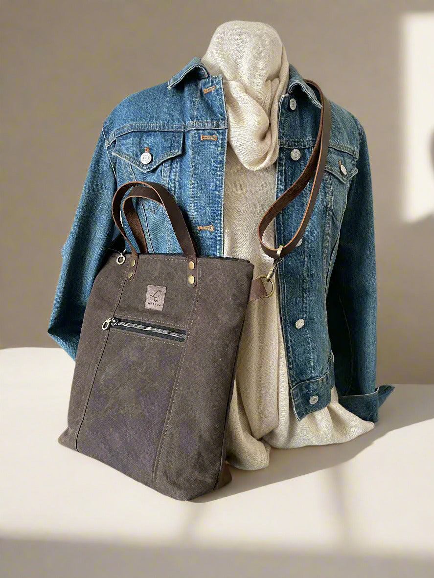 Lined crossbody/handbag in waxed canvas with leather handles and adjustable strap. Multiple zippered and slip pockets inside and out. Color choices are tan, chocolate brown, and olive green.