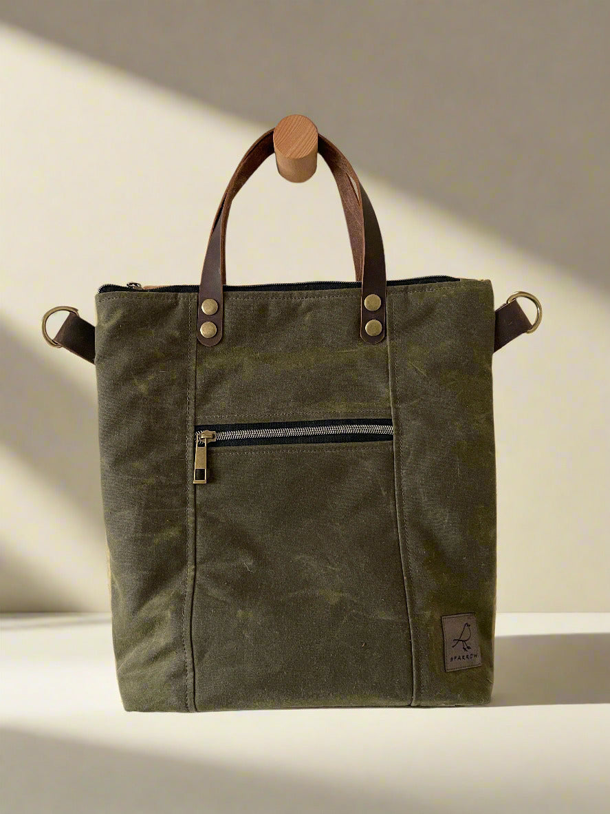Lined crossbody/handbag in waxed canvas with leather handles and adjustable strap. Multiple zippered and slip pockets inside and out. Color choices are tan, chocolate brown, and olive green.