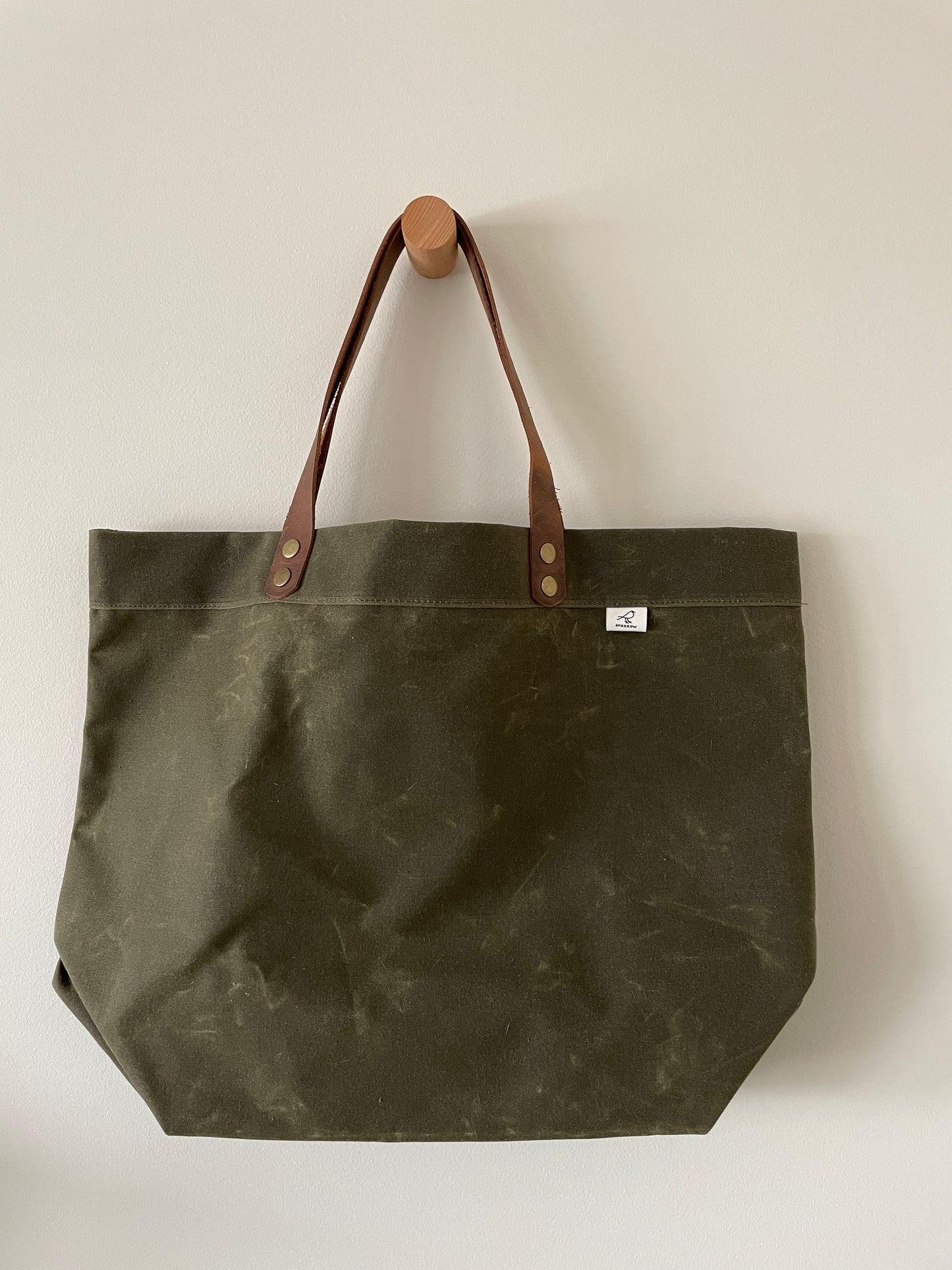Handmade simple waxed canvas shopping tote with full-grain leather handles, available in olive green or chocolate brown.