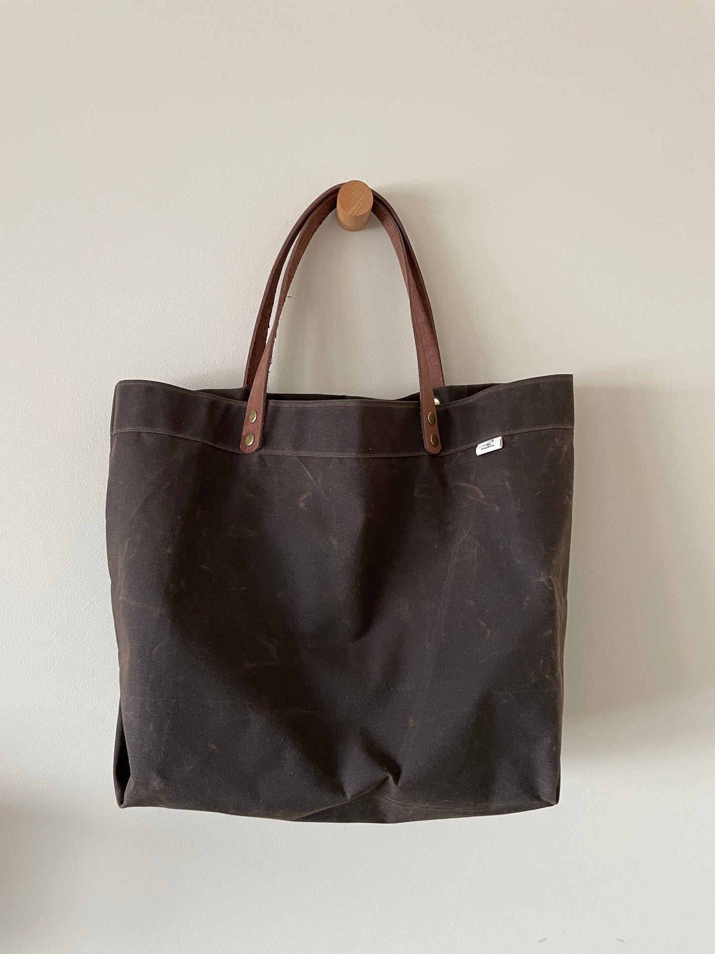 Handmade simple waxed canvas shopping tote with full-grain leather handles, in chocolate brown.