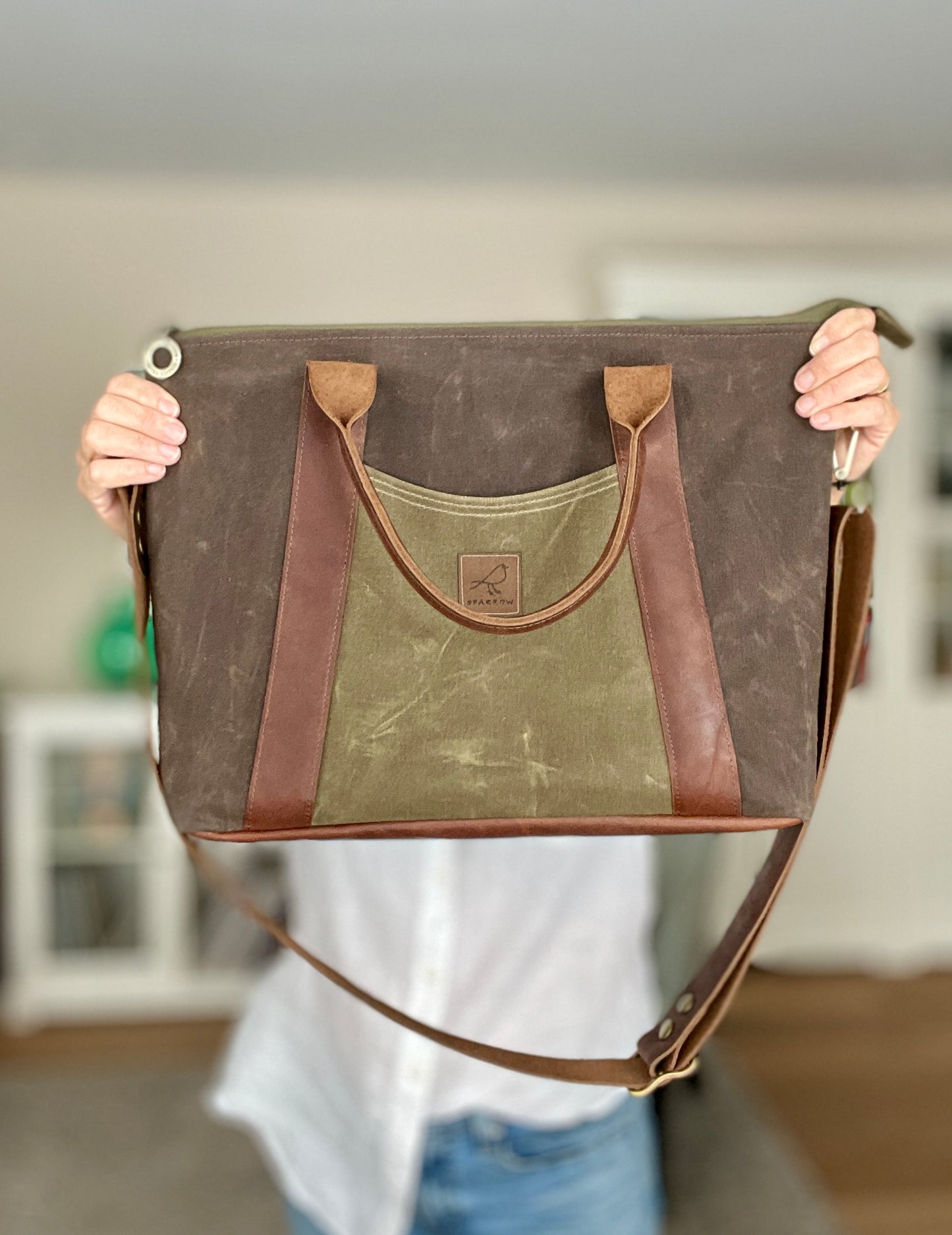 Oxbow crossbody/tote bag in waxed canvas exterior, with leather adjustable strap and handles. Two exterior front pockets, multiple inner pocket, fully lined. Chocolate brown waxed canvas, olive green waxed canvas on accent front and back pockets.
