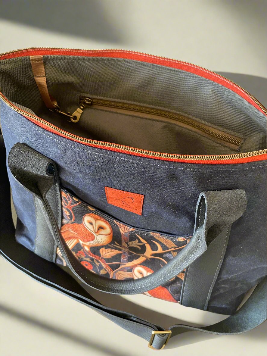 Oxbow crossbody/tote bag in waxed canvas exterior, with leather adjustable strap and handles. Two exterior front pockets, multiple inner pocket, fully lined. Navy waxed canvas, owl print on accent front and back pockets. Burnt orange zipper.