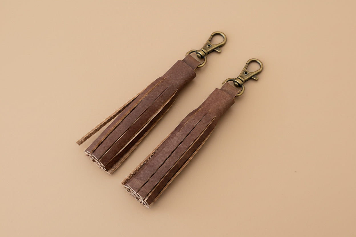 Two brown leather tassels with antique brass snaps