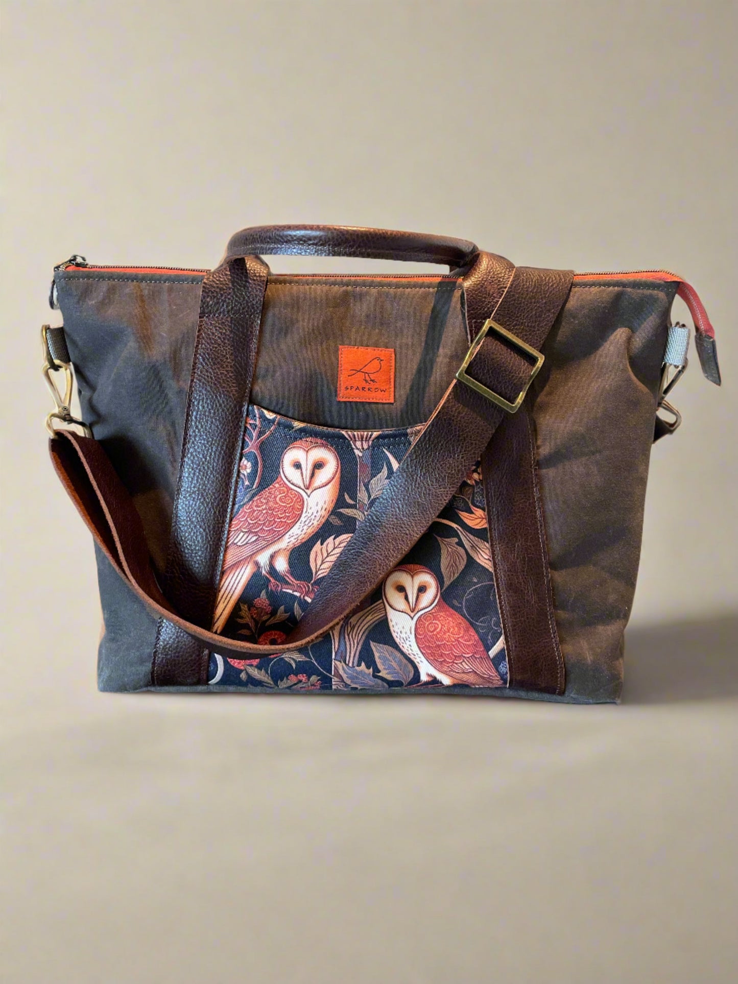 Oxbow crossbody/tote bag in waxed canvas exterior, with leather adjustable strap and handles. Two exterior front pockets, multiple inner pocket, fully lined. Chocolate brown waxed canvas, medieval owl print on accent front and back pockets.