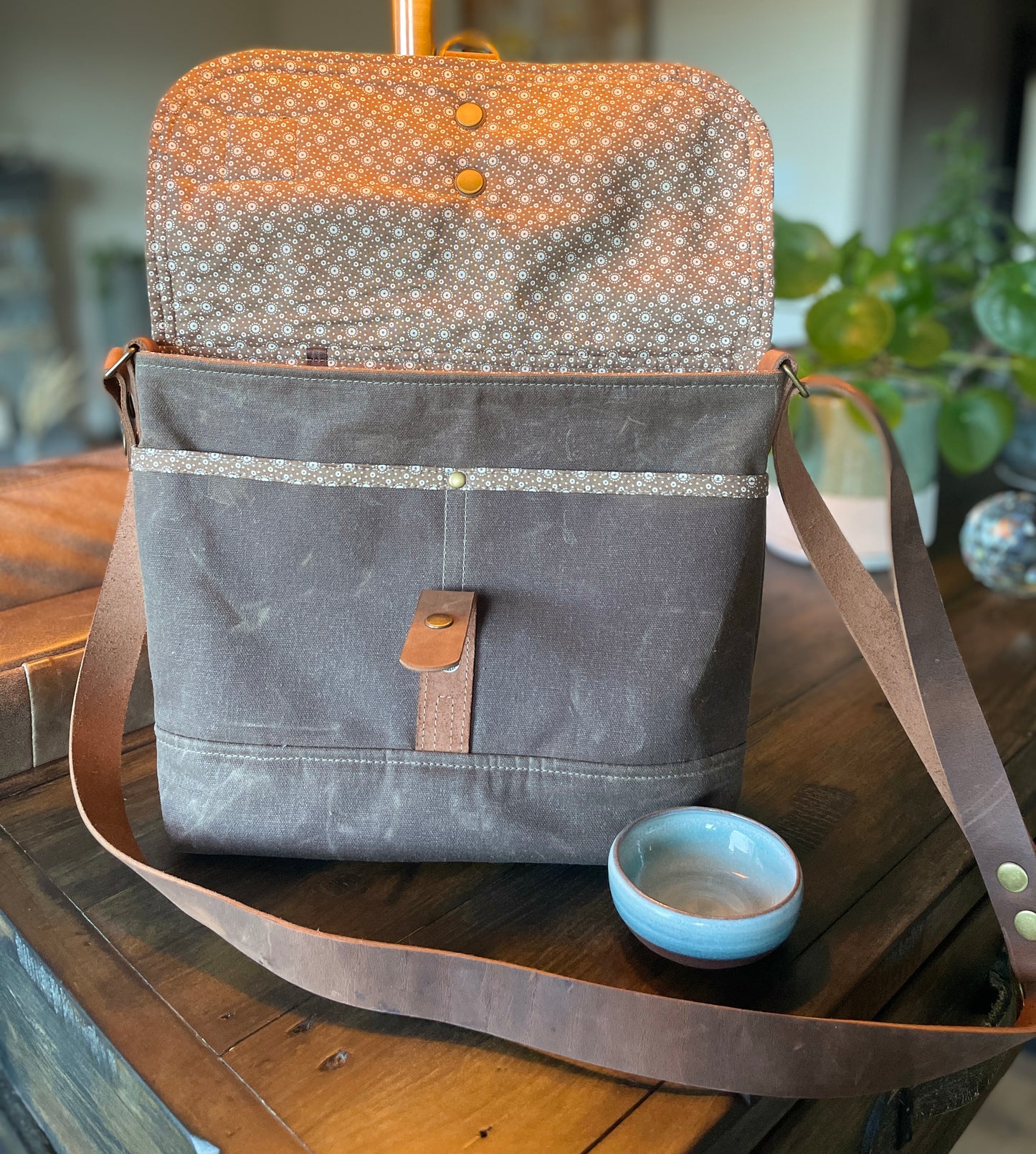 Shortie Messenger bag in all chocolate waxed canvas upper and base. Brown leather 1.5 inch adjustable strap with a leather snap closure. 