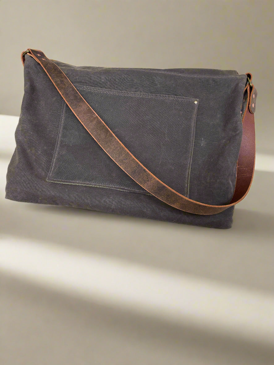 Back view of Attune crossbody bag in chocolate waxed canvas and olive green denim lining, for birthing stool, showing slip pocket for documents. 