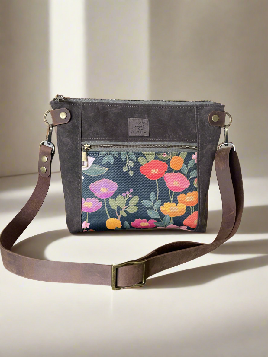 Cambridge crossbody bag in brown waxed canvas and Cloisonne floral front pocket accent print, with zippered front pocket and top closure. Adjustable leather strap. Handcrafted in Canada by Sparrow Handmade.