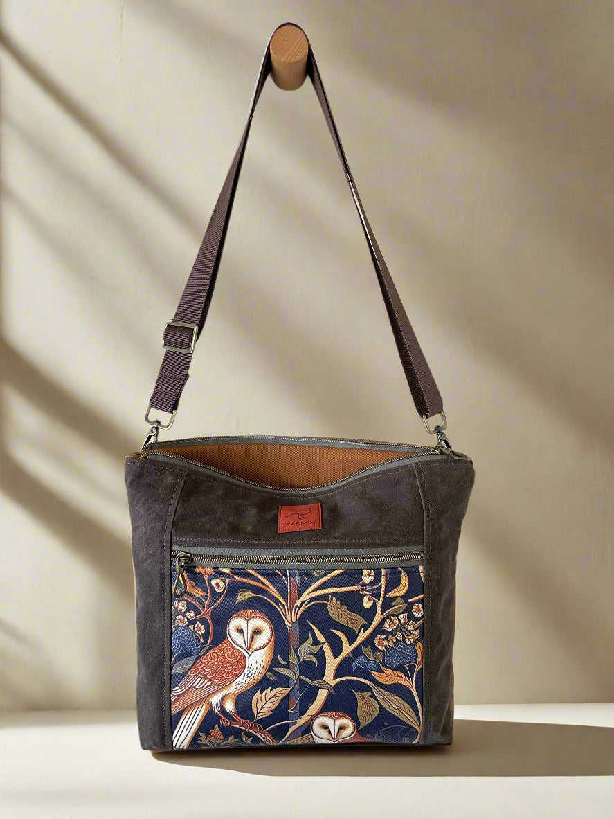 Vegan Cambridge crossbody bag in chocolate waxed canvas, medieval owls front accent, cinnamon denim lining, and brown nylon strap. Handcrafted in Canada by Sparrow Handmade.