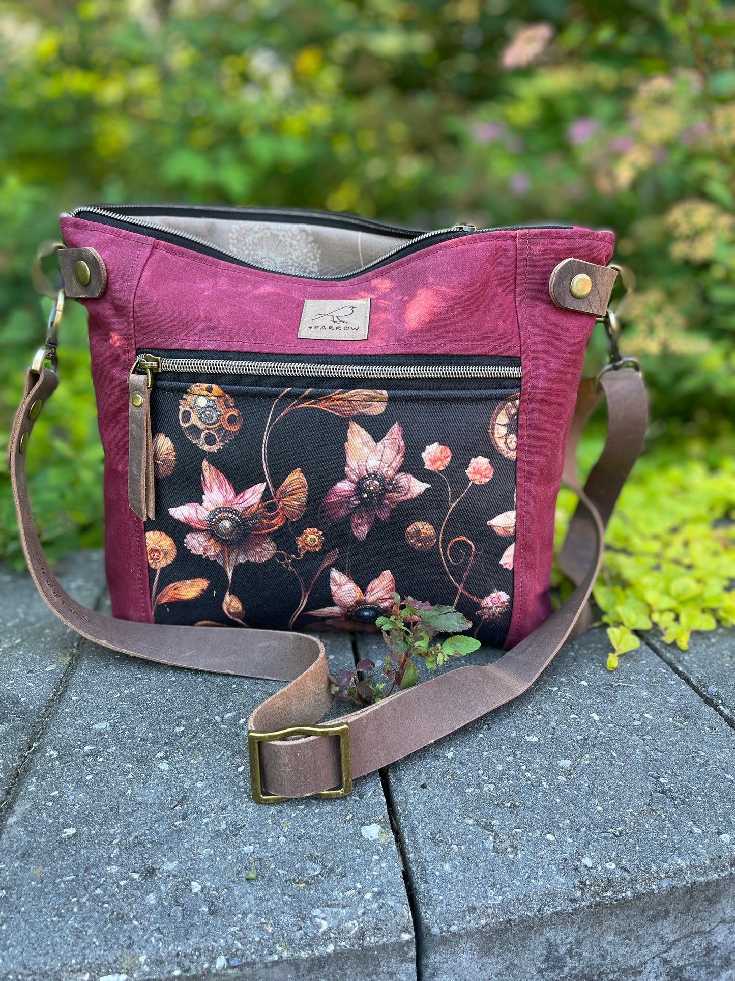 Sparrow Handmade Cambridge bag in cranberry waxed canvas and Steampunk floral accent.Lining is floral tan, with leather strap and closures. Handcrafted in Calgary Canada. 