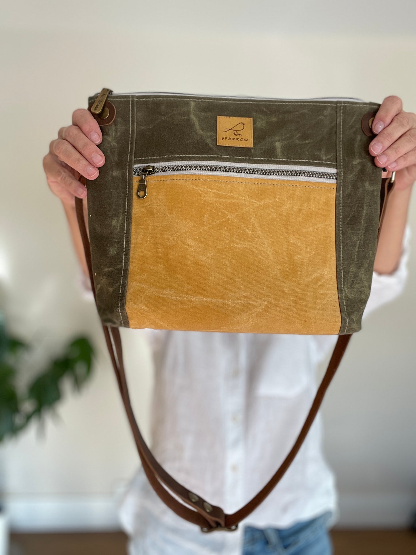 Cambridge crossbody bag in olive waxed canvas and ochre front pocket accent print, with zippered front pocket and top closure. Adjustable leather strap. Handcrafted in Canada by Sparrow Handmade.