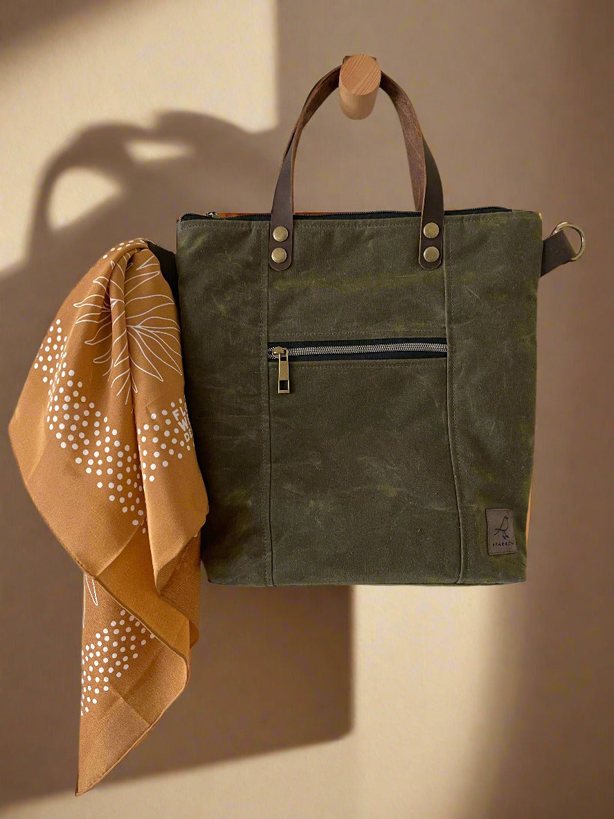 Lined crossbody/handbag in waxed canvas with leather handles and adjustable strap. Multiple zippered and slip pockets inside and out. Color choices are tan, chocolate brown, and olive green. 