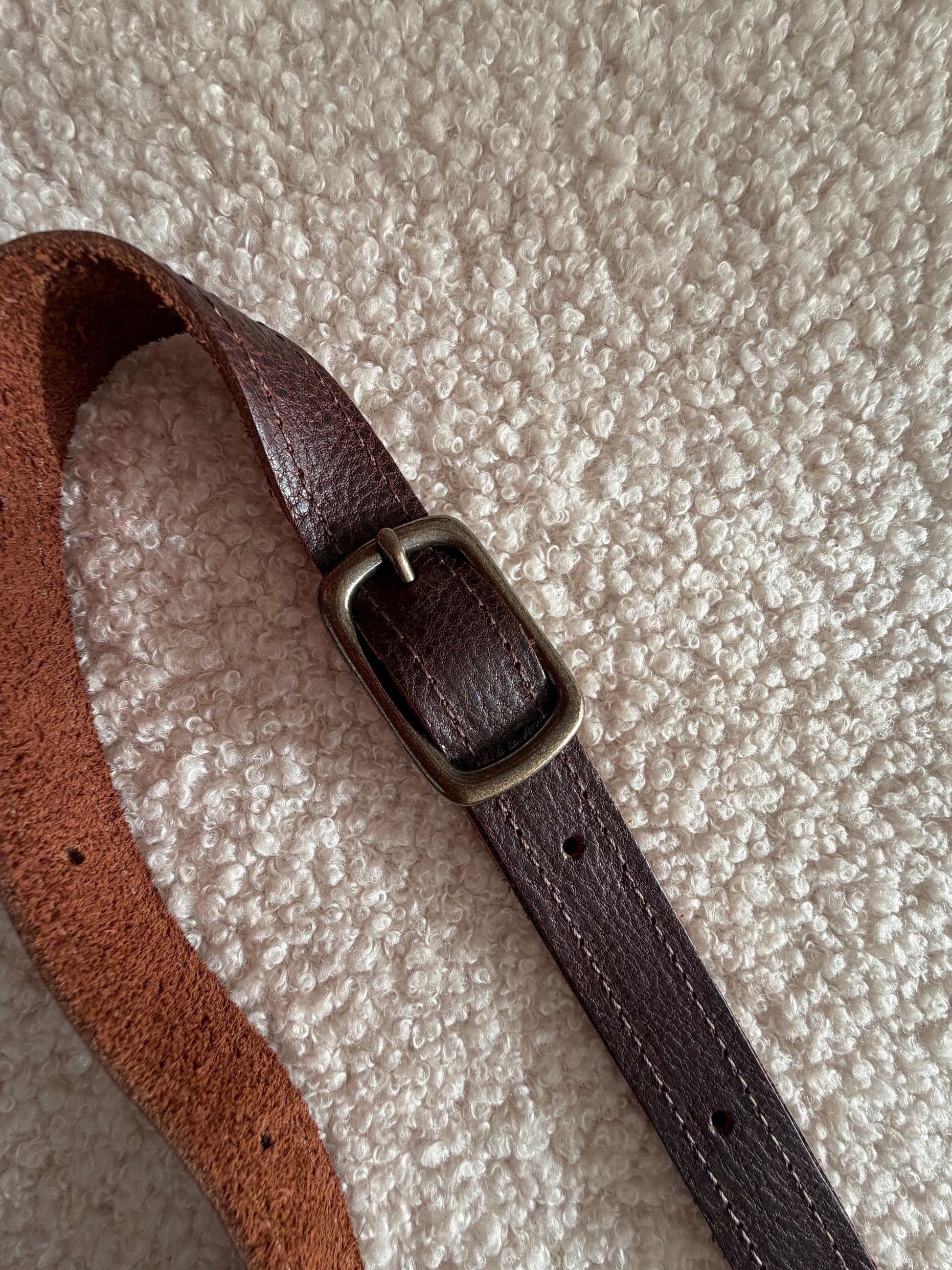 Close-up of leather strap and brass buckle on Scout small leather crossbody bag