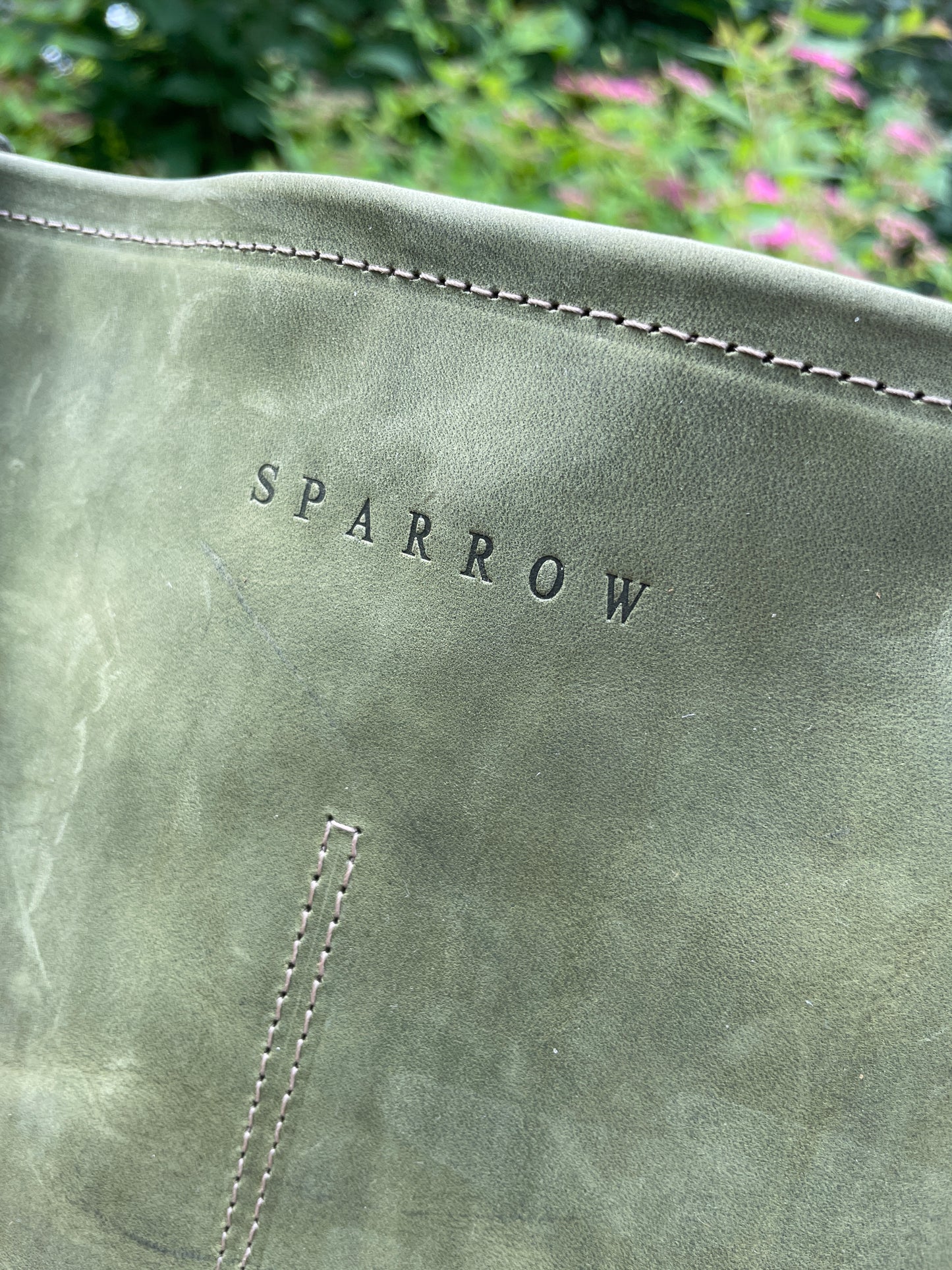 Closeup of front of Sierra leather bag showing brand and stitching lines