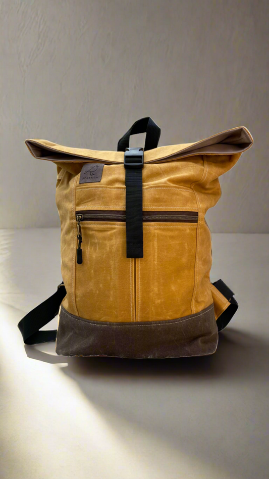 Roll-top backpack in ochre (yellow) waxed canvas and a brown waxed canvas base. Nylon webbing straps, buckle closure on top, hang tab on top. Zippered expandable front pocket. Unisex. 