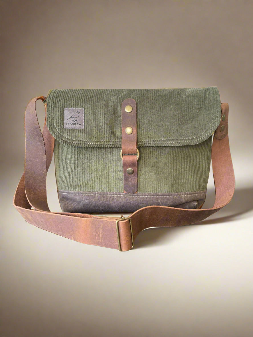 Shortie Messenger bag in olive green corduroy and a brown waxed canvas base. Brown leather 1.5 inch adjustable strap with a leather snap closure. Unisex bag. 