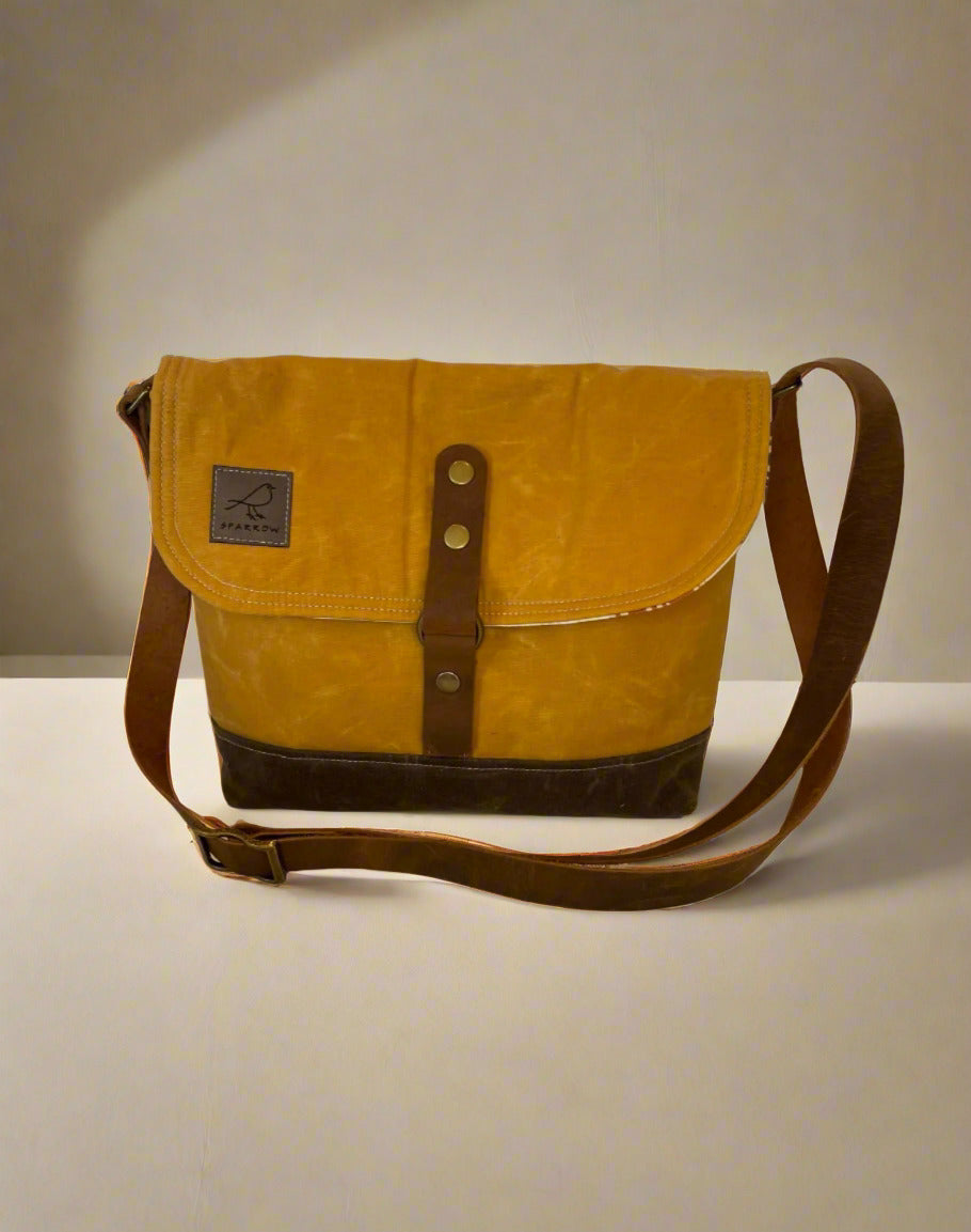 Shortie Messenger bag in ochre waxed canvas and a brown waxed canvas base. Brown leather 1.5 inch adjustable strap with a leather snap closure. Unisex bag. 
