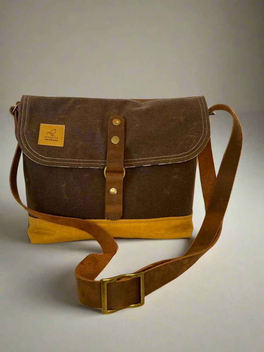 Shortie Messenger bag in brown waxed canvas main and ochre waxed canvas base. Brown leather 1.5 inch adjustable strap with a leather snap closure. Unisex bag. 