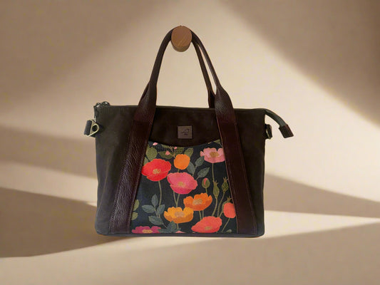 Mini Oxbow crossbody/hand bag in dark brown waxed canvas exterior, with poppy floral front and back accent pockets. Full grain leather strap and handles, zippered top, fully lined with multiple pockets. Handcrafted in Calgary Canada by Sparrow Handmade.