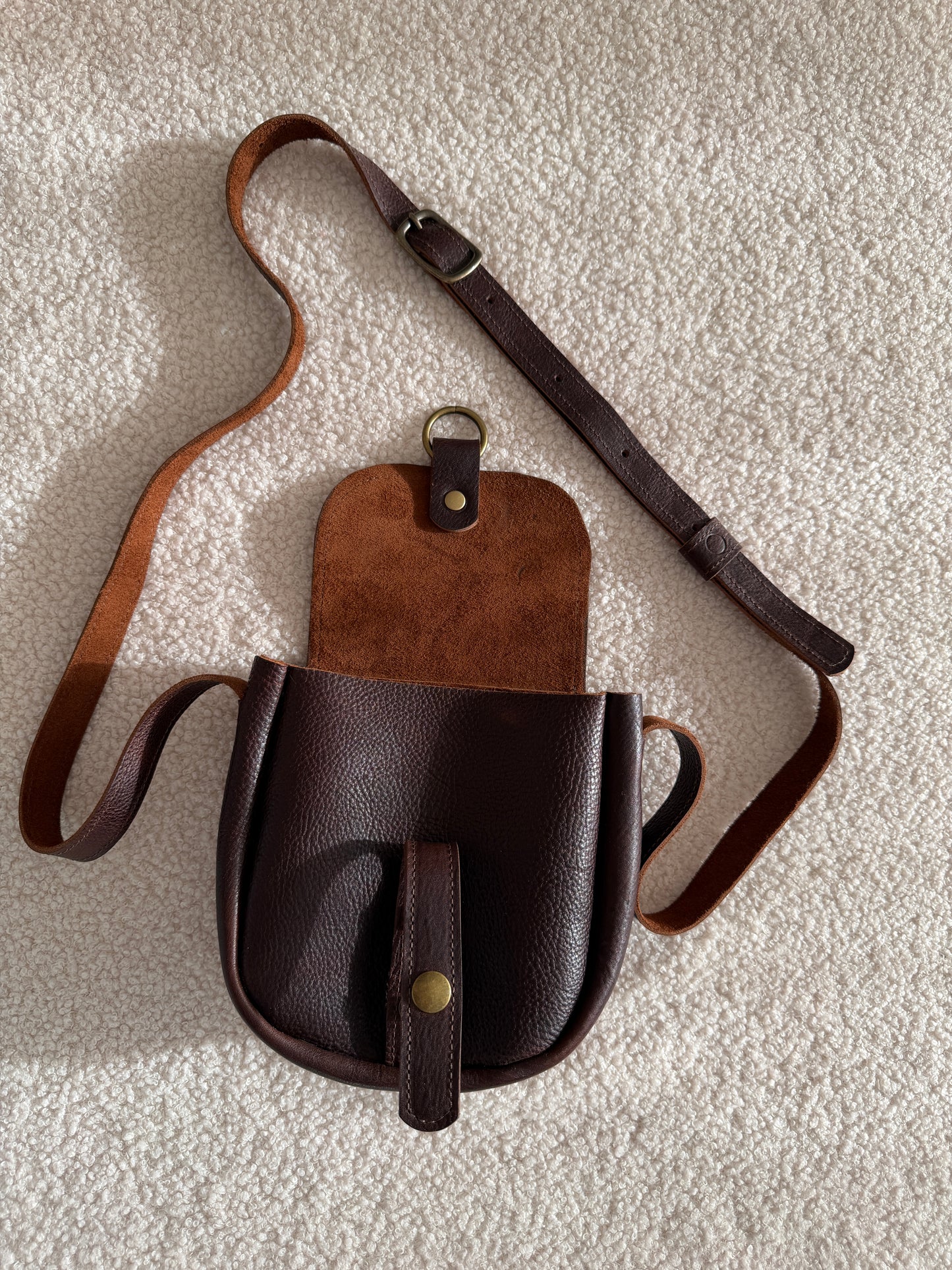 Scout - Brown leather crossbody bag on a textured surface