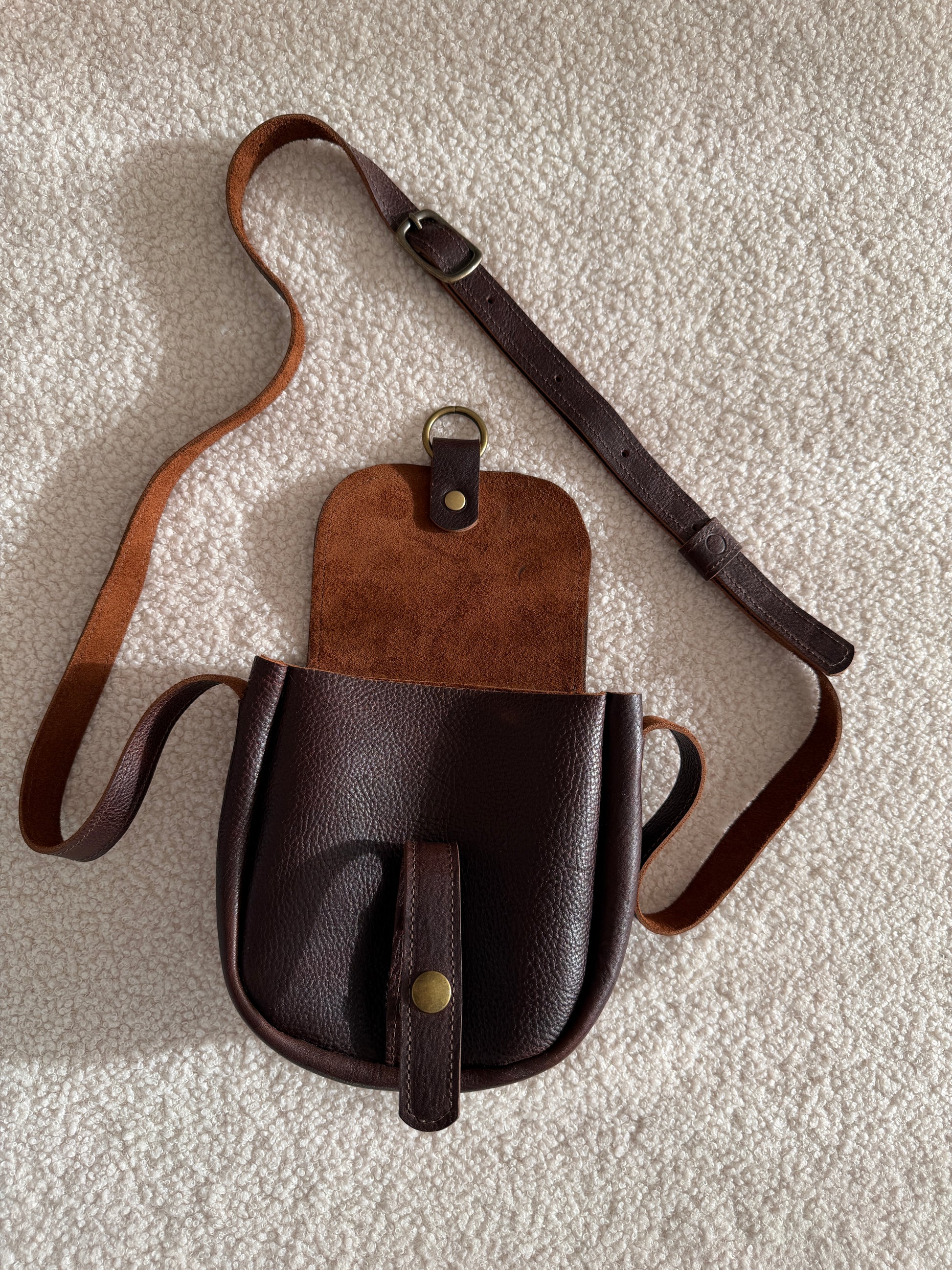 Scout - Brown leather crossbody bag on a textured surface