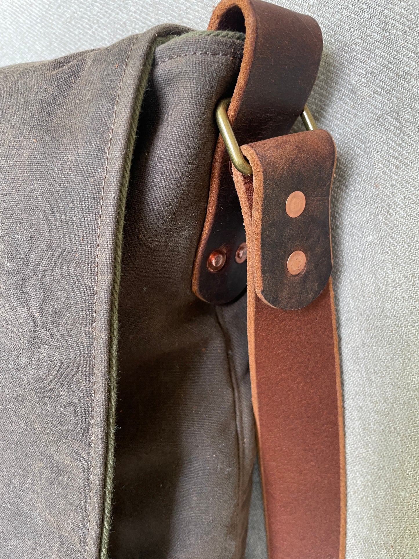 Side detail view showing leather strap with copper rivets on Attune birthing stool bag. 