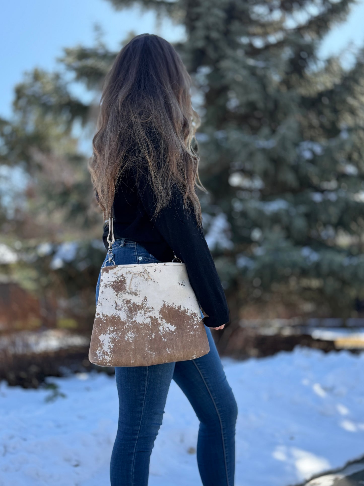 Side view of model carrying a Sierra leather crossbody bag, in Guernsey patterned full-grain leather. 