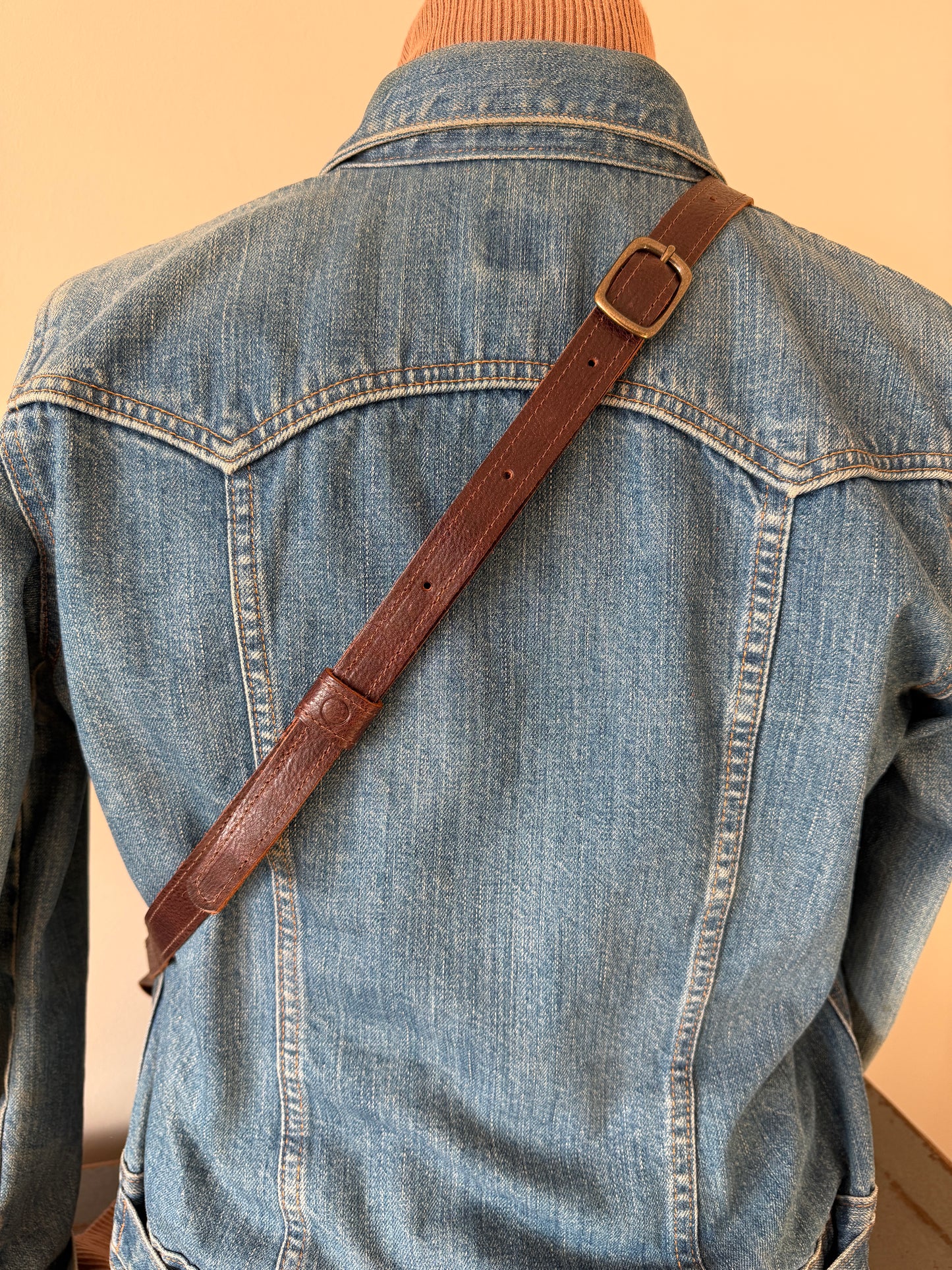 Scout strap worn crossbody on model, featuring brass buckle