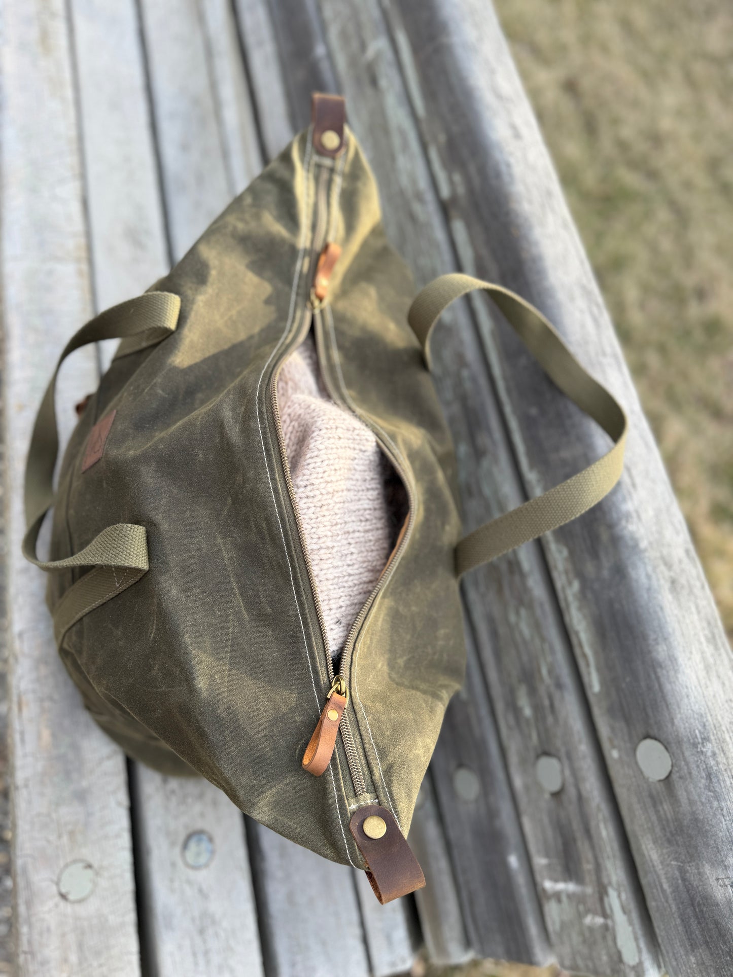 Weekender waxed canvas bag in olive green handmade in Canada by Sparrow Handmade. Top view, with knit sweater peeking out. 