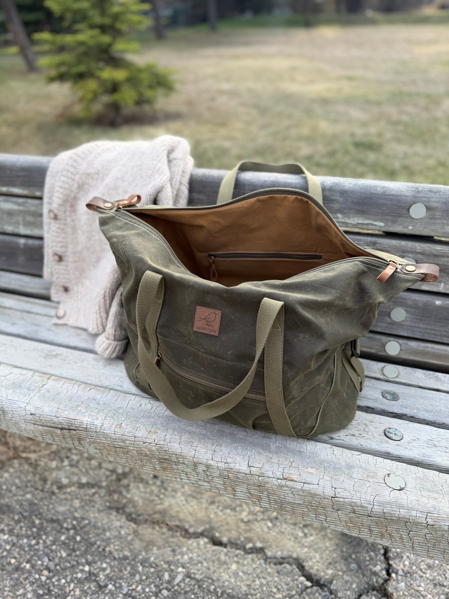 Weekender waxed canvas bag in olive green handmade in Canada by Sparrow Handmade. Shown with the zipper open, exposing the cinnamon colored canvas lining