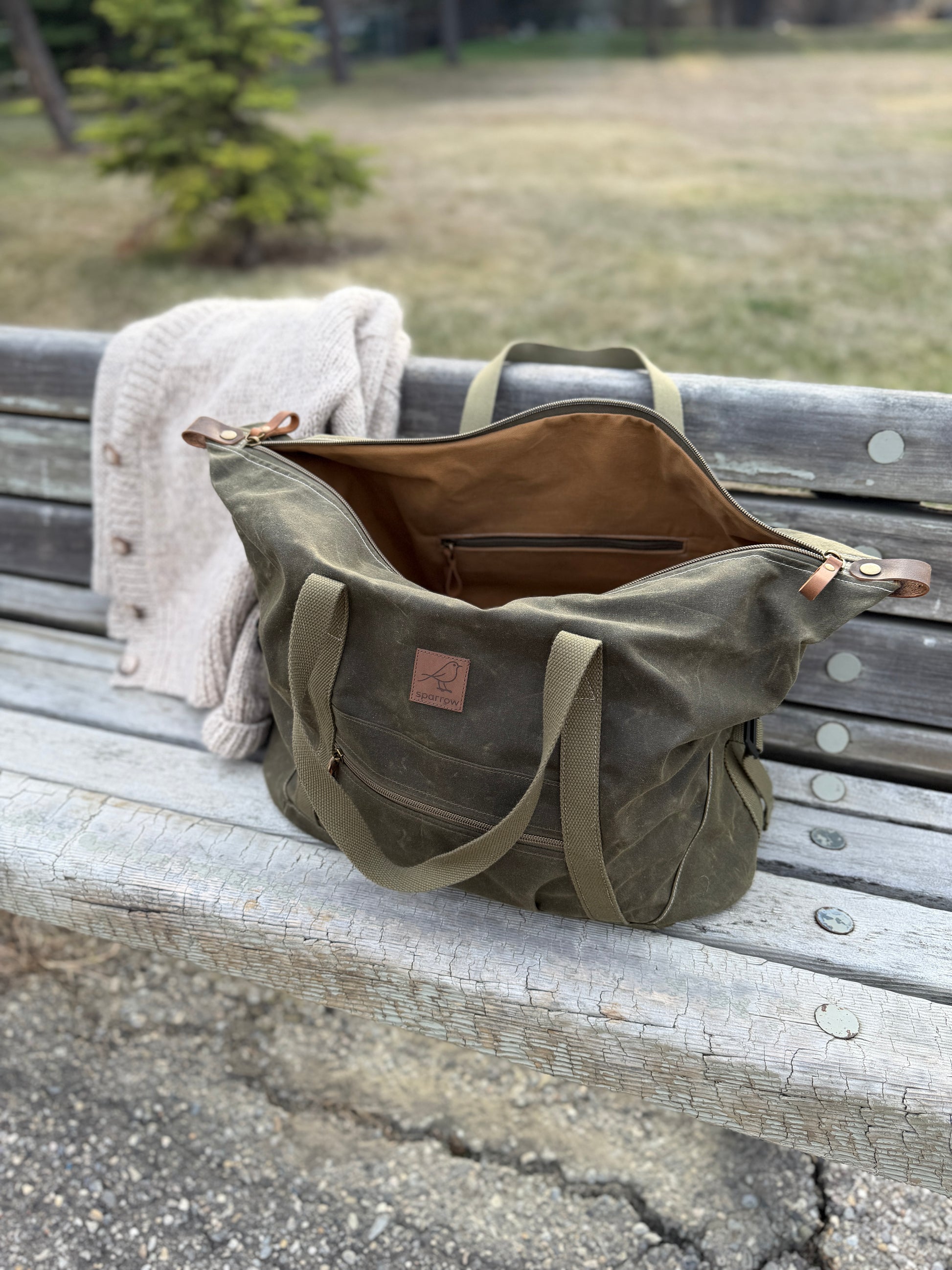 Weekender waxed canvas bag in olive green handmade in Canada by Sparrow Handmade. Shown with the zipper open, exposing the cinnamon colored canvas lining