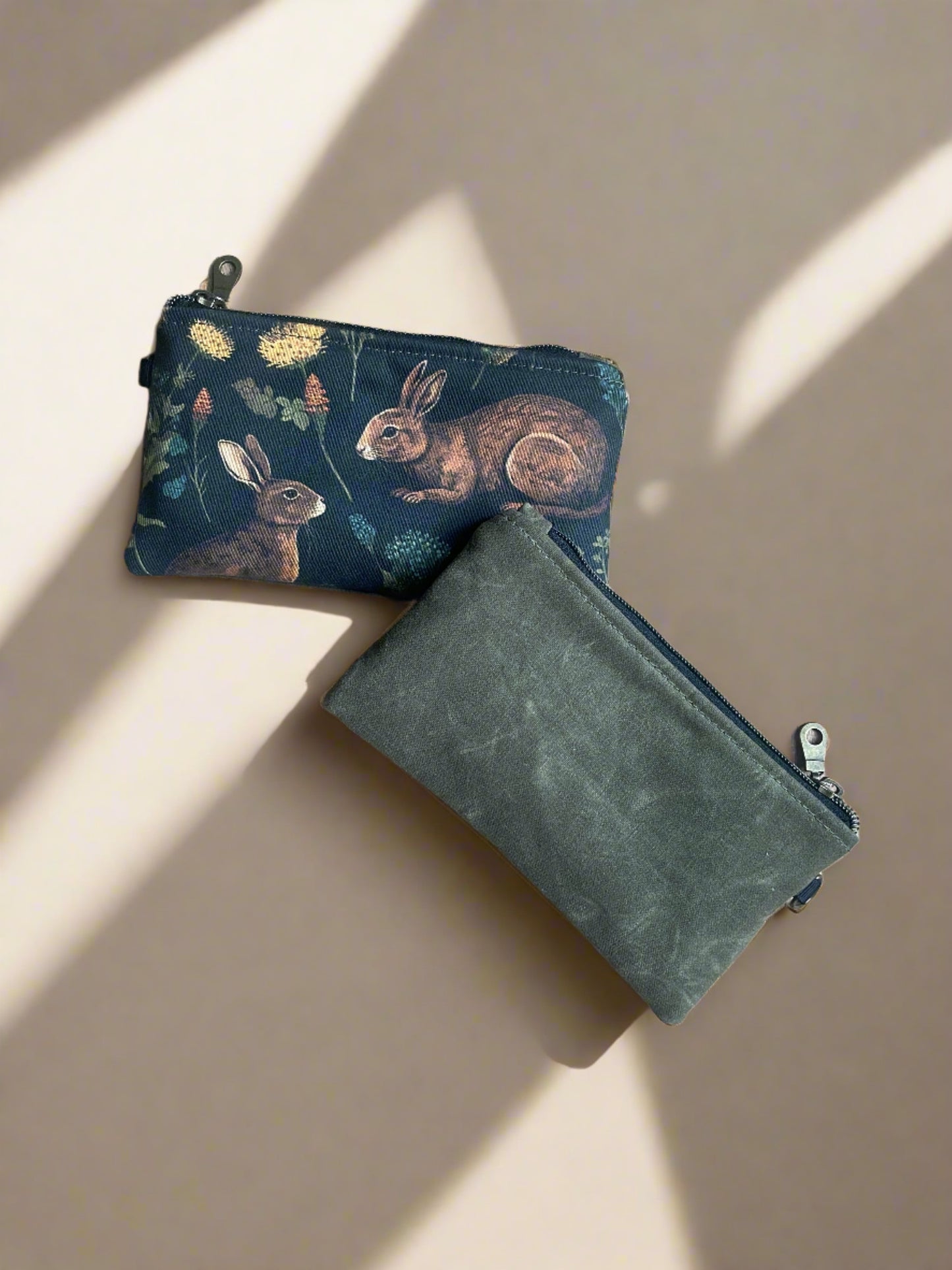 Zippered pouch in olive waxed canvas on the back and medieval rabbit print on the front. Handcrafted in Canada by Sparrow Handmade. 